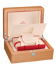 Omega watch presentation box with an open wooden exterior, cream interior, red trim, and a watch cushion visible inside. The Omega wordmark appears on the inner lid.