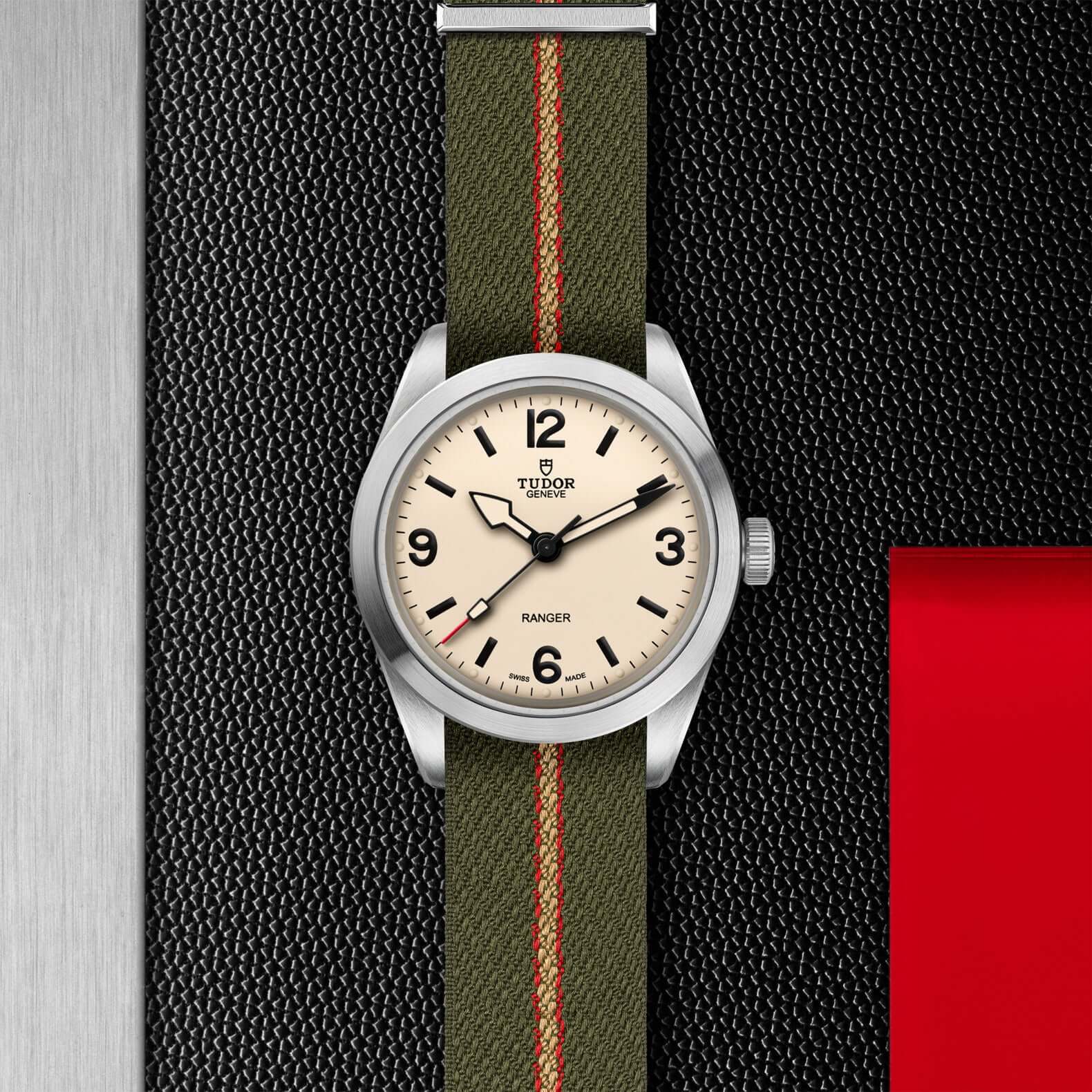Watch with a green strap and beige dial on a textured black background
Tudor Ranger M79950-0011 Bandiera Jewellers