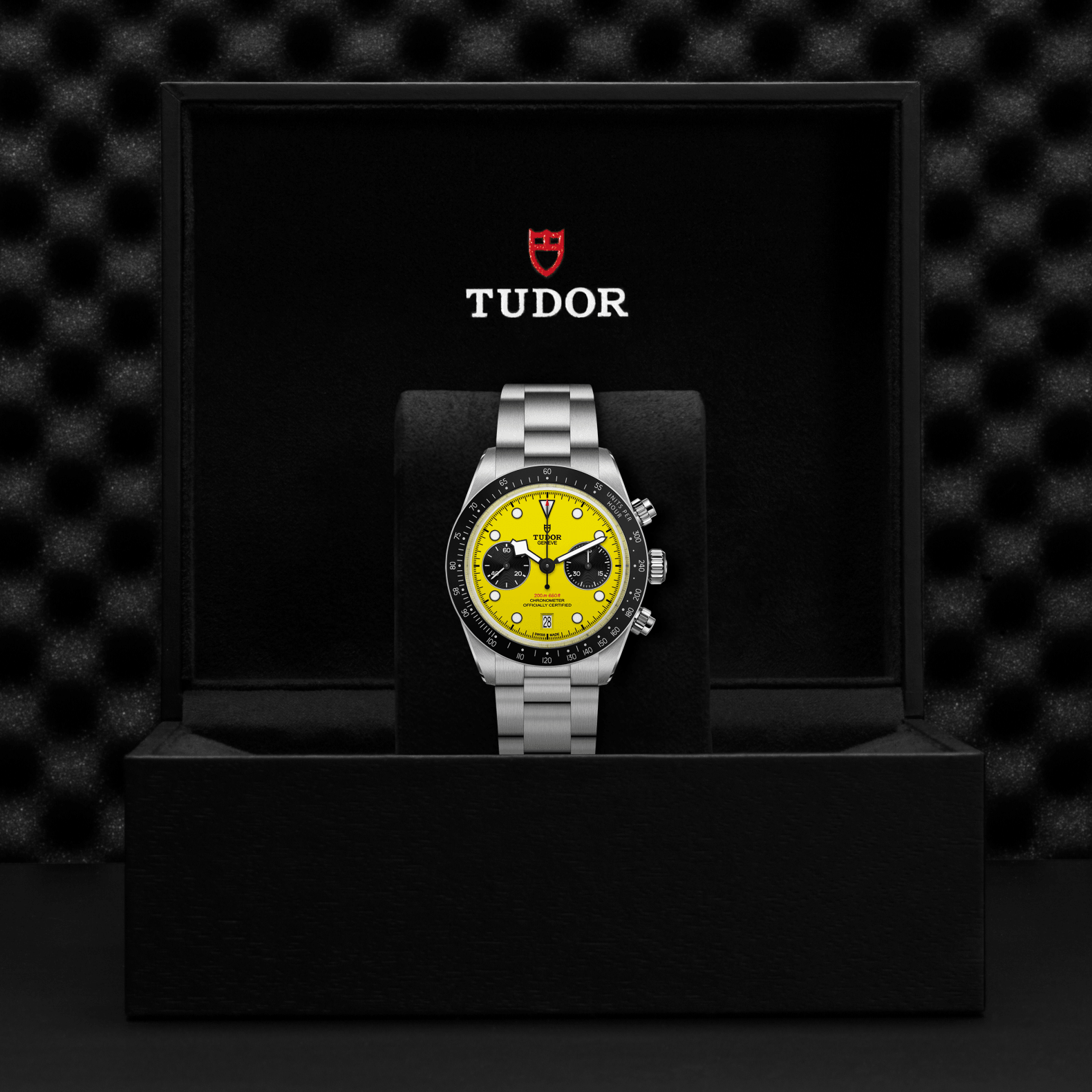 Tudor watch with yellow face and silver bracelet on a black display stand against a textured black background.
TUDOR Black Bay Chrono 39 M79310N-0001 Bandiera Jewellers