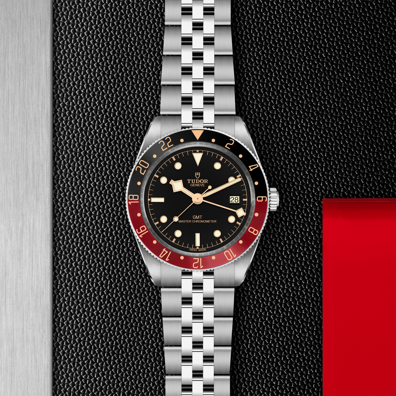 Silver watch with black face and red bezel on a textured black background
Tudor Black Bay 58 GMT M7939G1A0NRU-0003 Bandiera Jewellers