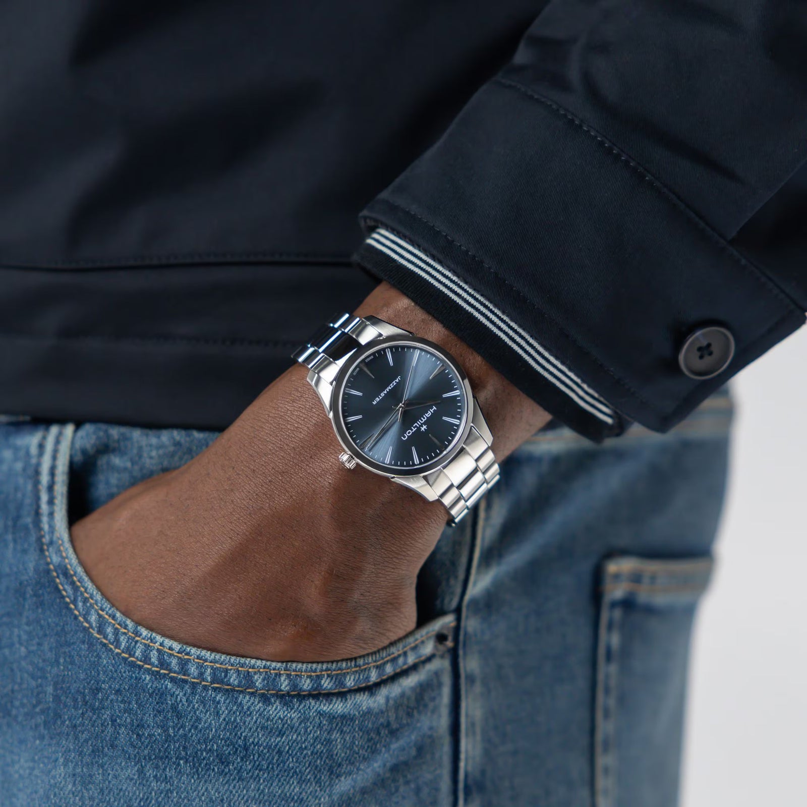 Hand wearing a silver watch with a dark face, against a blurred background.

Hamilton Jazzmaster Quartz 40mm H32461141 Bandiera Jewellers