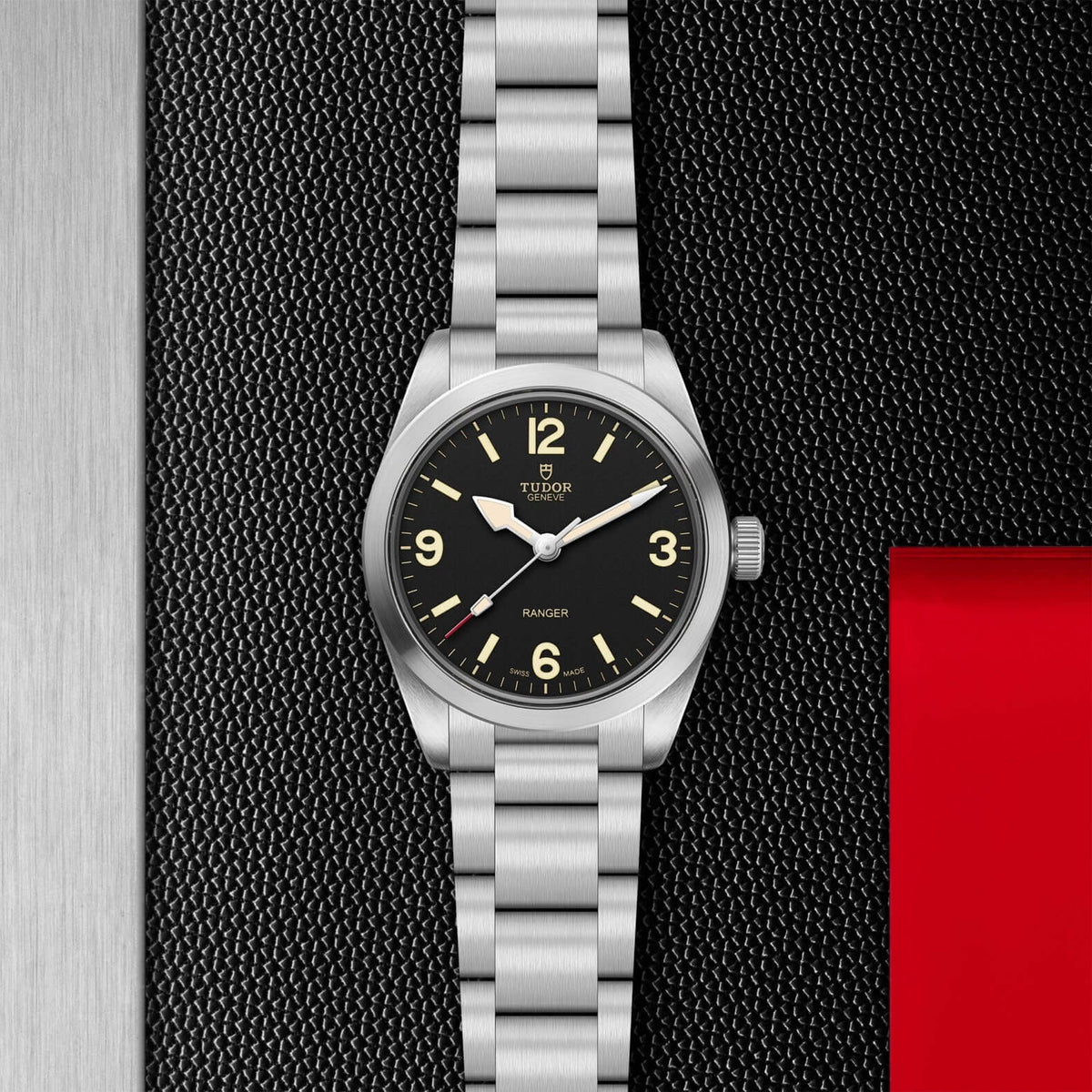 Silver watch with black dial on a textured black background

Tudor Ranger M79930-0001 Bandiera Jewellers