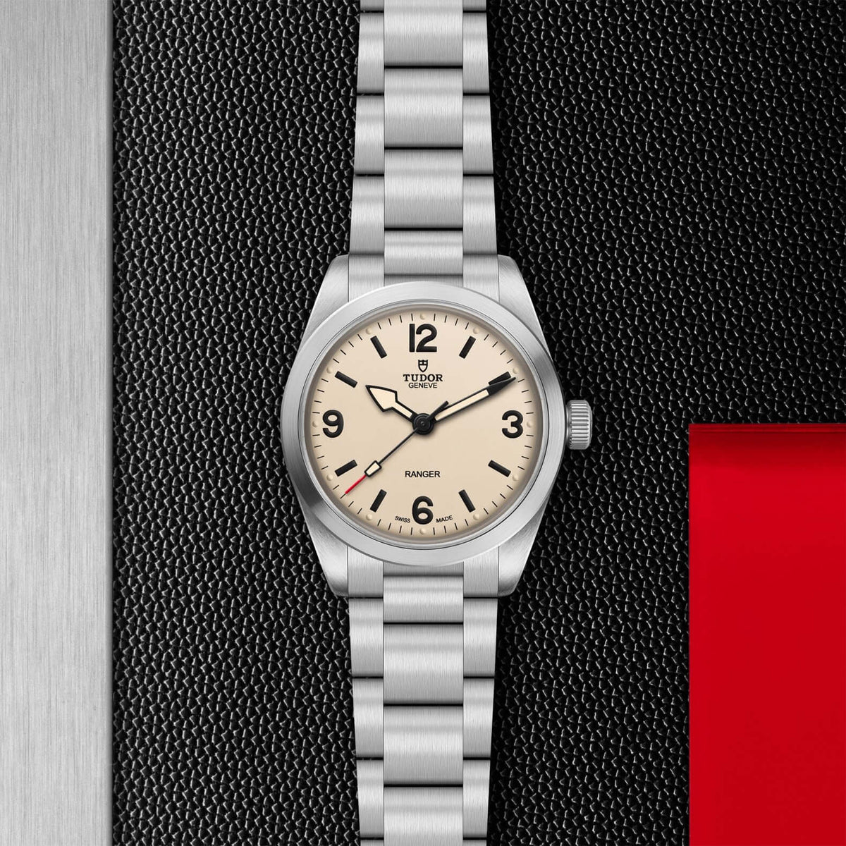 Silver Tudor watch with beige dial on a textured black background

Tudor Ranger M79930-0007 Bandiera Jewellers
