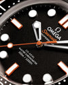 Close-up of an Omega Seamaster watch face with black dial and orange accents.