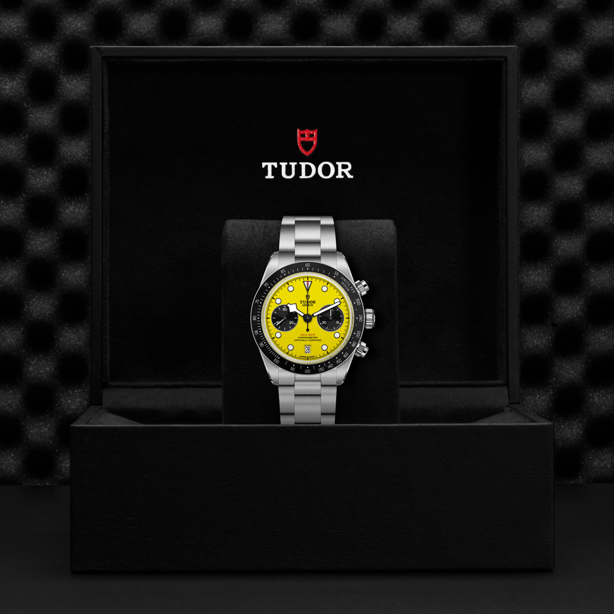 Tudor watch with yellow face and silver bracelet on a black display stand against a textured black background.

TUDOR Black Bay Chrono 39 M79310N-0001 Bandiera Jewellers